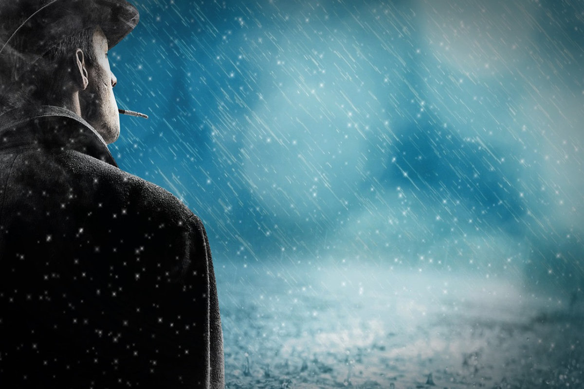 Mann von schräg hinten bei Nacht im Regen