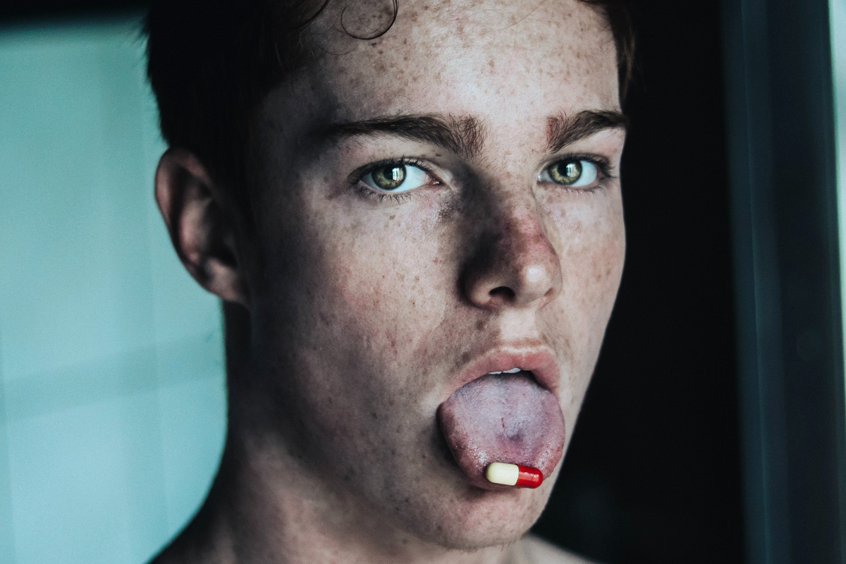 Junger Mann mit einer Kaspel an der rausgestreckten Zunge